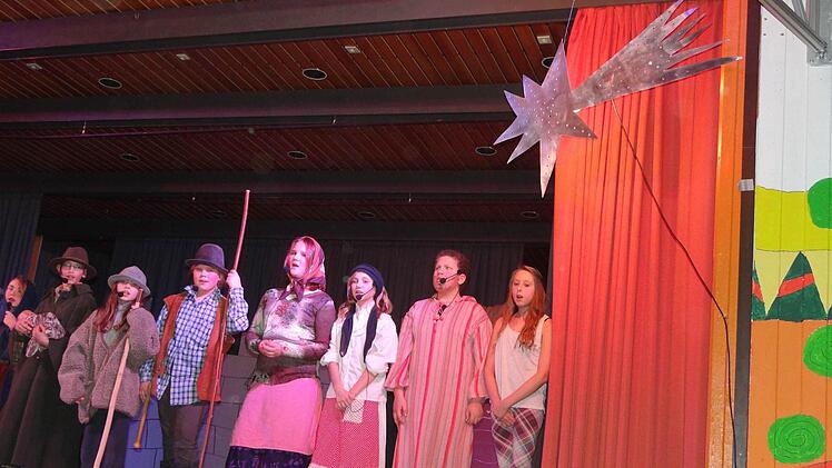 Ganz in Eigenregie meistern die Schülerinnen und Schüler ihren Auftritt am Weihnachtskonzert. Der leuchtende Stern kann ihnen dabei nur bedingt den Weg weisen. Aber sie haben eine Souffleuse positioniert, die bei Textunsicherheit unterstützt. Foto: Johanna Eckert