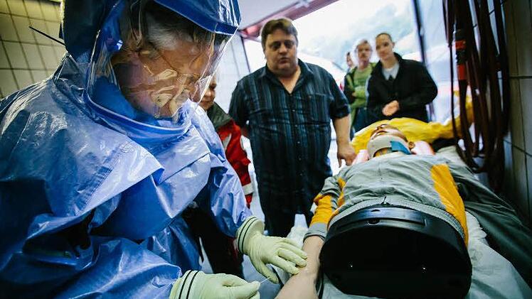 Ob ein Notarzt in dem Schutzanzug Blut abnehmen kann, prüft Gesundheitsamtsleiter Helmut Weiß an einem Dummy. Foto: Hendrik Steffens