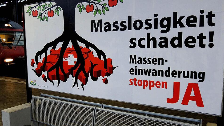 Ein Poster der Schweizerischen Volkspartei (SVP) gegen "Masseneinwanderung" steht auf dem Bahnhof SBB in Basel. In Blick haben die Initiatoren vor allem die Deutschen. Foto: Thomas Burmeister/dpa