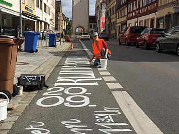 Die Kalligrafin Melina Müller, die aus Pfaffendorf stammt, zeichnete Hinweise auf die Freitagsdemo in Haßfurt an verschiedenen Stellen auf die Straßen, hier die Hauptstraße. Die Aktion hatte die Initiative "ParentsforFuture" beauftragt. Die Finanzierung übernahm Maintal Konfitüren Haßfurt. Foto: privat