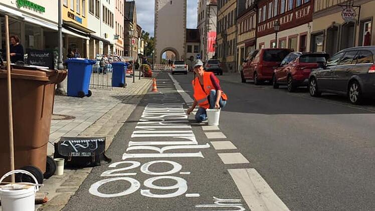 Die Kalligrafin Melina Müller, die aus Pfaffendorf stammt, zeichnete Hinweise auf die Freitagsdemo in Haßfurt an verschiedenen Stellen auf die Straßen, hier die Hauptstraße. Die Aktion hatte die Initiative "ParentsforFuture" beauftragt. Die Finanzierung übernahm Maintal Konfitüren Haßfurt. Foto: privat