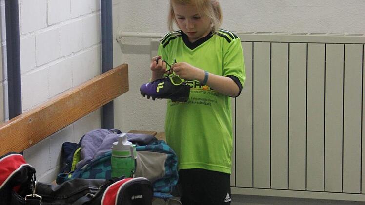 Lena schnürt beziehungsweise entschnürt die Fußballschuhe...