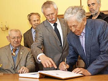 Alfred Stühler trägt sich ins goldene Buch der Stadt ein. Links: Arnold Samuels