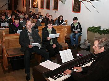 Regionalkantor Erich Staab (rechts) bei der Übungsstunde in der Wachenrother Kirche Sankt Gertrud. Organist Peter Arnold (erste Reihe links) ist zuversichtlich, dass sich die Gemeinde bald an das neue Gotteslob gewöhnen wird. Foto: Andreas Dorsch