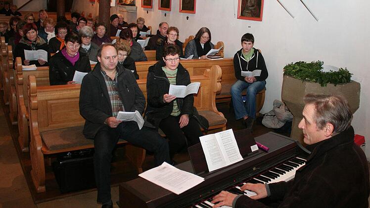 Regionalkantor Erich Staab (rechts) bei der Übungsstunde in der Wachenrother Kirche Sankt Gertrud. Organist Peter Arnold (erste Reihe links) ist zuversichtlich, dass sich die Gemeinde bald an das neue Gotteslob gewöhnen wird. Foto: Andreas Dorsch