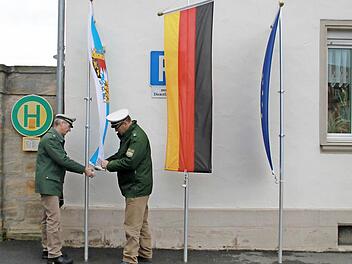 Die Polizisten Peter Wolf und Ralph Hanschkow (von links) hissen die bayerische Staatsflagge, die deutsche und die europäische Fahne vor der Bad Staffelsteiner Polizeistation auf Halbmast. Foto: Thomas Heuchling