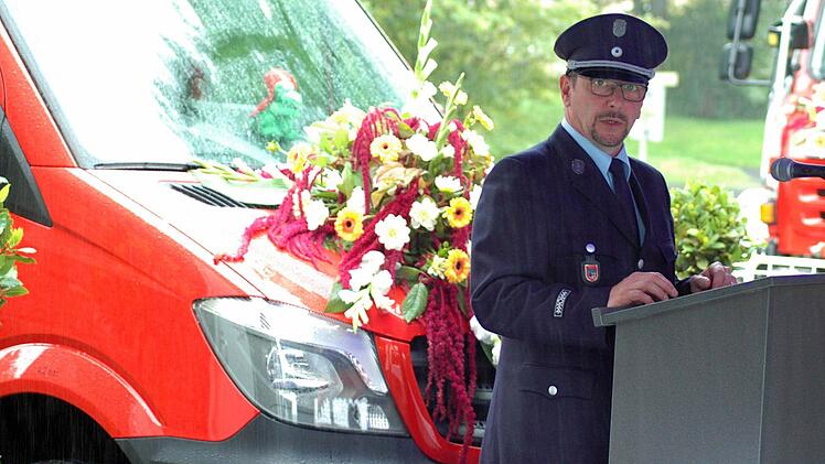 Michael Hackl von der Feuerwehr Oberwildflecken dankt in strömendem Regen allen Beteiligten, die an der Beschaffung des neuen Feuerwehrfahrzeuges mitgewirkt haben. Foto: Sebastian Schmitt-Mathea
