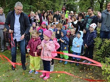 Bürgermeister Bernd Drummer durchschneidet mit Lisa und Amelie das Band. Die restliche Kinderschar kann es kaum erwarten, dass der neue Spielplatz endlich freigegeben wird. Foto: Franz Galster