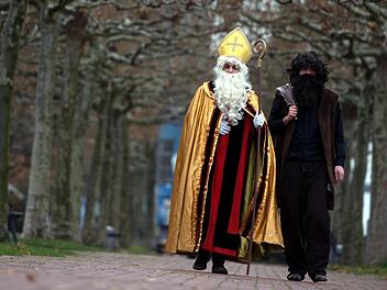 Mitglieder vom Bund der Deutschen Katholischen Jugend gehen als Nikolaus (l) und Knecht Ruprecht verkleidet am Rheinufer entlang. Eine Gr&uuml;nen-Politikerin aus Nordrhein-Westfalen h&auml;lt den strengen Gehilfen des Nikolaus f&uuml;r &uuml;berholt. Foto: Federico Gambarini/dpa