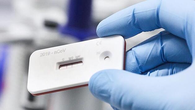 Ein Wissenschaftler zeigt einen Corona Schnelltest im Leibnitz Institut f&uuml;r Photonische Technologien.  Foto: Bodo Schackow/dpa