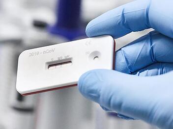 Ein Wissenschaftler zeigt einen Corona Schnelltest im Leibnitz Institut für Photonische Technologien.  Foto: Bodo Schackow/dpa