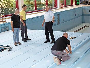 Bürgermeister Helmut Fischer, der Kämmerer Gerd Bergmann und Schwimmmeister Roland Mann überzeugten sich vom Fortschritt der Hubbodensanierung im Michelauer Bad. Insgesamt eine Woche werden die Arbeiten dauern.  Foto: Klaus Gagel