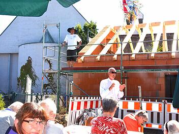 Der Vorsitzende des Diakonievereins Maroldsweisach, Pfarrer Wolfgang Scheidel, heißt zum Richtfest willkommen. Im Hintergrund die katholische Herz-Jesu-Kirche. Auf dem Dachstuhl wartet bereits Dieter Hepp, um seinen Richtspruch zu halten.  Foto: Gerhardt Schmidt