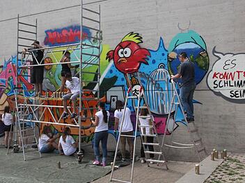 Unter Anleitung des Nürnberger Künstlers Carlos Lorente (auf dem Gerüst links) sprühten 13 Jugendliche der Mittelschule Mühlhausen ein Graffiti im Pausenhof. Foto:Daniel Ruppert