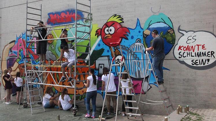 Unter Anleitung des Nürnberger Künstlers Carlos Lorente (auf dem Gerüst links) sprühten 13 Jugendliche der Mittelschule Mühlhausen ein Graffiti im Pausenhof. Foto:Daniel Ruppert