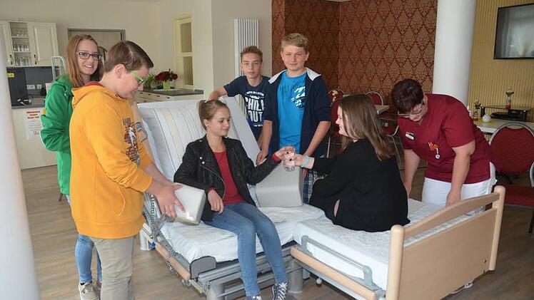 Im Rollenspiel bereiteten sich die Firmlinge mit der Ergotherapeutin auf ihre Aufgabe am Vis-a-Vis- Pflegebett vor wie man Essen und Trinken richtig reicht und den Pflegebedürftigen im Bett zum Sitzen aufrichtet. Foto: Heike Schülein