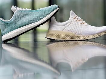 Zwei Schuhe, die Adidas gestern am Rande der Pressekonferenz präsentierte: Das Obermaterial des linken besteht aus Ozean-Müll, die Sohle des rechten wurde mit einem 3D-Drucker hergestellt. Foto: Daniel Karmann, dpa