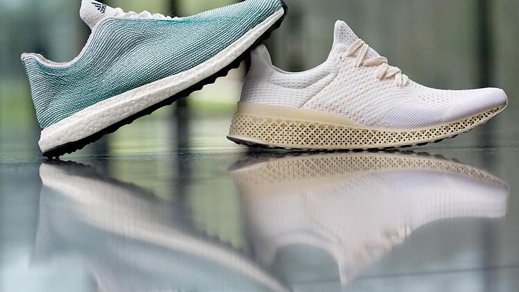 Zwei Schuhe, die Adidas gestern am Rande der Pressekonferenz präsentierte: Das Obermaterial des linken besteht aus Ozean-Müll, die Sohle des rechten wurde mit einem 3D-Drucker hergestellt. Foto: Daniel Karmann, dpa