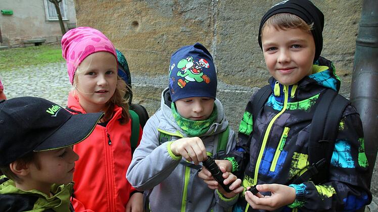 Eine Geocaching-Tour auf Martin Luthers Spuren bietet jetzt die Initiative Rodachtal in Heldburg an. Am Donnerstag konnten Schüler der Grundschule Hellingen sie erstmals testen. Gespannt erwarten Nick, Lukas und Helene (von rechts), was sich im ersten Cache wohl versteckt. Foto: Bettina Knauth