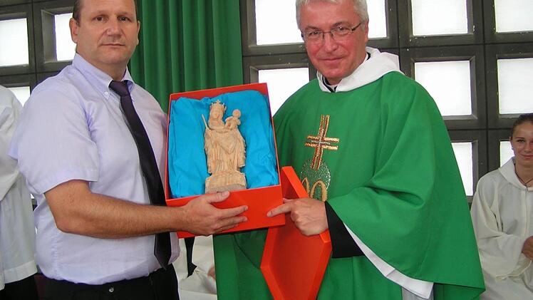 Pfarrgemeinderatsvorsitzender Rüdiger Knauer (links) überreicht Pfarrer Gerhard Möckel als Geschenk der Pfarrei eine Marienstatue. Foto: Heidi Amon