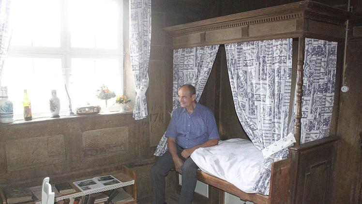 Artur Fischer sitzt auf dem Himmelbett, in dem 1632 der Feldherr Wallenstein übernachtete, als er mit seinen Soldaten durch den Itzgrund zog. Das Wallenstein-Zimmer befindet sich in Fischers historischem Anwesen in der Gleußener Ortsmitte. Foto: Matthias Einwag