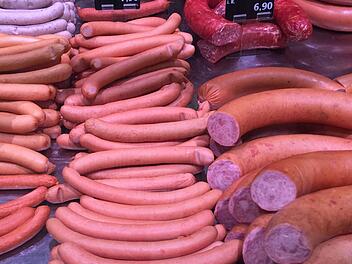 Eine appetitliche Auslage von Würsten in verschiedenen Sorten und Größen. Hinweistafeln zeigen Preise und Auswahl der Produkte an.