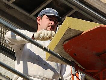 Ein Verputzer bringt den Vollwärmeschutz an der Fassade eines Gewo-Gebäudes an. Foto: Benedikt Borst