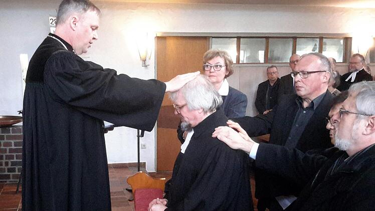 Bodo Bergk (kniend) ist der neue Pfarrer der evangelischen Kirchengemeinde Wildflecken. Dekan Till Roth (links) führte den Geistlichen am Sonntag im Beisein der Vertrauensfrau Christine Gehrlein und der Assistenten in den Dienst ein. Foto: Rolf Pralle