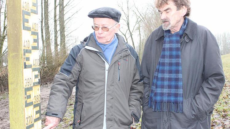 Hoffen auf dauerhaften Hochwasserschutz: Die Wiesener Manfred Utz und Hans Bramann (v. l.) an der Pegelmesslatte am Damm.