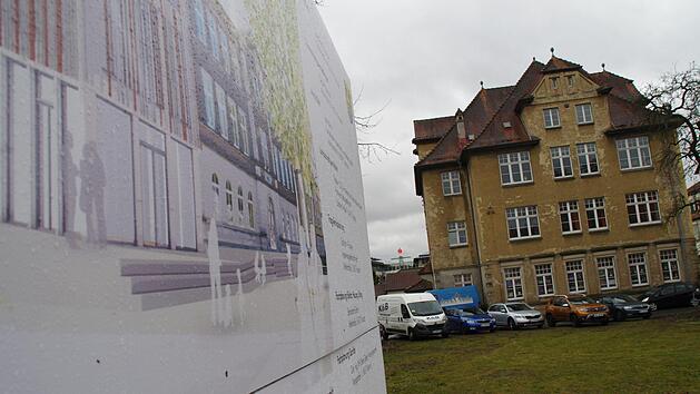 Die Baustellentafel zeigt, wie die herausgeputzte VHS n&auml;chstes Jahr aussehen soll. Die ehemalige Stadtb&uuml;cherei wirkt dagegen in die Jahre gekommen.