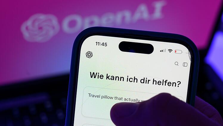 Smartphone mit dem KI-Chatbot ChatGPT vor dem Logo von OpenAI