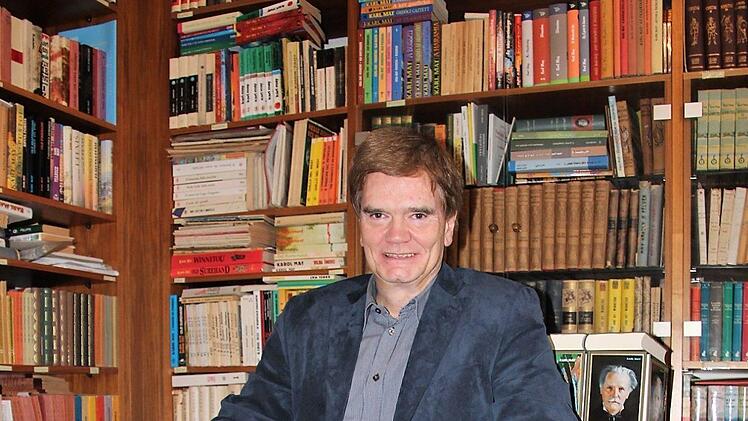 Er steht auf Karl May  - und manchmal sitzt er sogar auf dessen Werken: Bernhard Schmid,  Leiter des Bamberger Karl-May-Verlags.  Diana Fuchs
