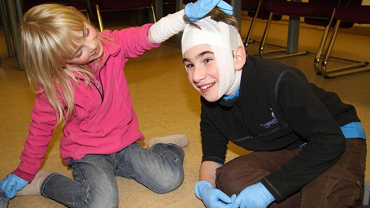 Florian Uhl (10) hat sich einen Kopfverband anlegen lassen - Michelle Bergeron (12) und Leonie Tulke (10) sind schon echte Erste-Hilfe-Profis. Michelle ist in der Max-Hundt-Schule, Leonie Tulke ist am Markgraf-Georg-Friedrich-Gymnasium und sie ist schon sechs Jahre beim Roten Kreuz