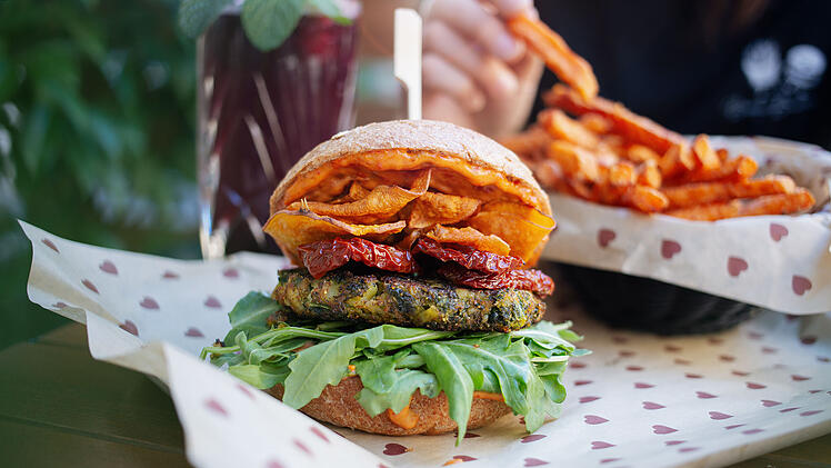 Veganer Hanf im Glück Burger mit einem Grünkohl-Hanf Patty, getrockneten Tomaten, Süßkartoffelchips und veganer Tomaten-Mayo im Burgerheart.