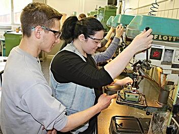 Kleine "Berührungsängste" sind zu erkennen, als Azubi Sebastian Werb (links) der Schülerin Melanie Schneck (rechts) an er Bohrmaschine Hilfestellung gibt. Foto: Helmut Will