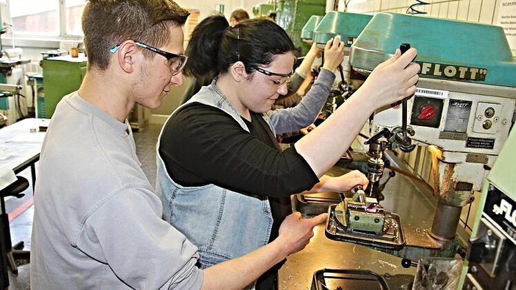 Kleine "Berührungsängste" sind zu erkennen, als Azubi Sebastian Werb (links) der Schülerin Melanie Schneck (rechts) an er Bohrmaschine Hilfestellung gibt. Foto: Helmut Will