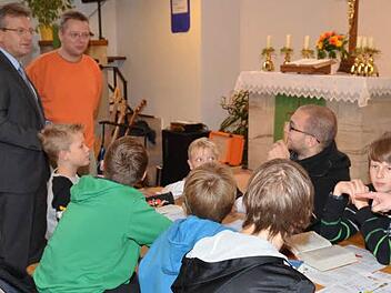 Bürgermeister Rainer Detsch (links) musste bei seiner Stippvisite beim Kinder-Bibeltag selbst Rede und Antwort stehen. "Beten sie auch, Herr Bürgermeister?", lautete eine Frage. Mit im Bild ist Organisator David Reinhold (stehend, rechts). Foto: Karl-Heinz Hofmann