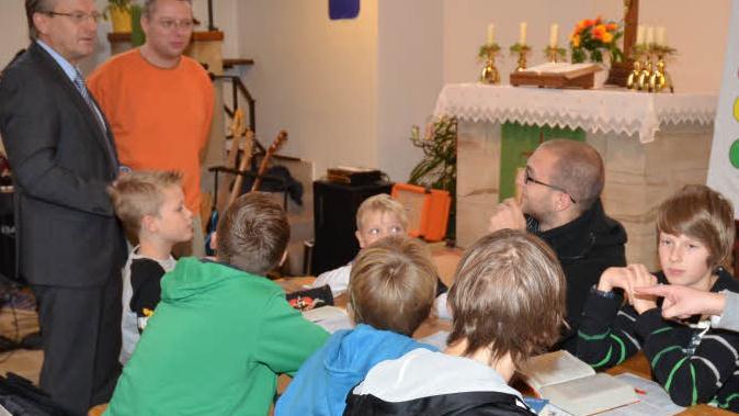Bürgermeister Rainer Detsch (links) musste bei seiner Stippvisite beim Kinder-Bibeltag selbst Rede und Antwort stehen. "Beten sie auch, Herr Bürgermeister?", lautete eine Frage. Mit im Bild ist Organisator David Reinhold (stehend, rechts). Foto: Karl-Heinz Hofmann