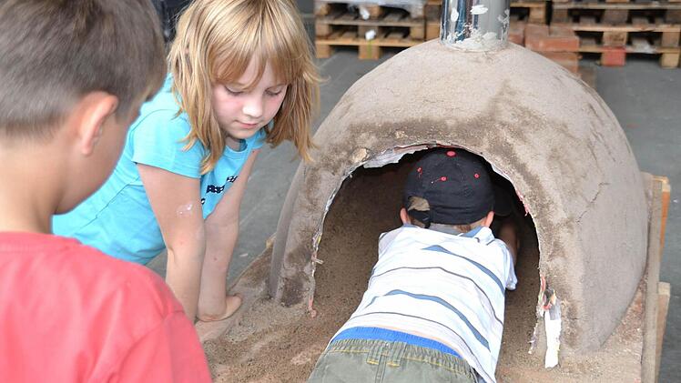 Der Sand muss raus, bevor zum ersten Mal Feuer im selbst gebauten Lehmofen gemacht werden kann. Fotos: Sonja Adam, Uschi Prawitz und Markus Roider
