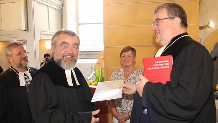 Dekan Christoph Liebst überreicht die Urkunde für die Pfarrstelle an Pfarrer Wolfgang Leikert. Foto: Michael Stelzner