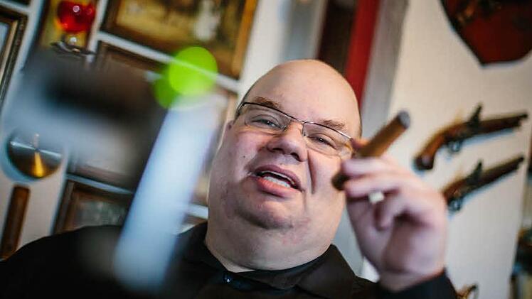 Immer wenn ihm eine Zigarre besonders positiv oder negativ auffällt, bespricht er sie. Dabei sitzt er auf einem Chesterfield-Sessel zwischen Gemälden und antiken Pistolen. Foto: Hendrik Steffens