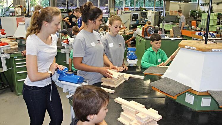 Die Azubis Franzi, Katharina und Celina (hinten von links), geben den Kindern Ratschläge für den Bau eines Nistkastens. Foto: Helmut Will