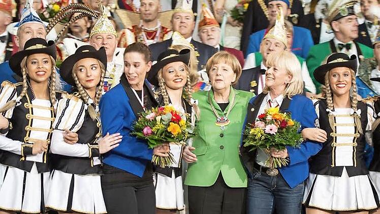 Gruppenbild mit Kanzlerin: Die Damen in Blau sind Dominique und Ramona Scholz, Trainerinnen der Tanzsportgarde Coburger Mohr. Die Dame in Grün ist Angela Merkel. Die Mädchen in Schwarz-Weiß gehören zur Königsgarde des "Tanzmohren". Foto: Bern von Jutrczenka/dpa