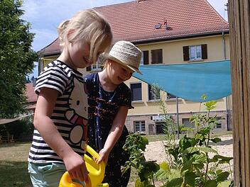 Sofia (vorne) und Ella helfen jeden Tag wie selbstverständlich im Kindergarten beim Gießen.