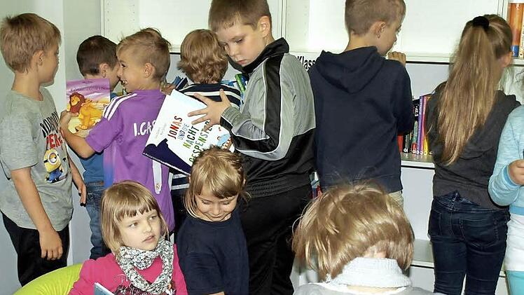 Lea Deuerling (links) und Lena Klinger haben es sich auf dem gelben Sitzsack in der neuen Bibliothek gemütlich gemacht, Luca Ströhlein schaut, was die beiden lesen.  Foto: Susanne Deuerling