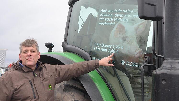 BBV-Kreisobmann Martin Flohrschütz zeigt bei der Demo auf der Lauterer Höhe auf ein Plakat an seinem Traktor.