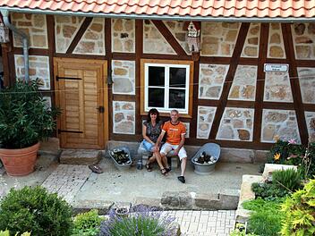 Die Hofmanns sitzen im Hof an ihrem denkmalgeschützten behutsam sanierten Haus. Foto: Bettina Knauth