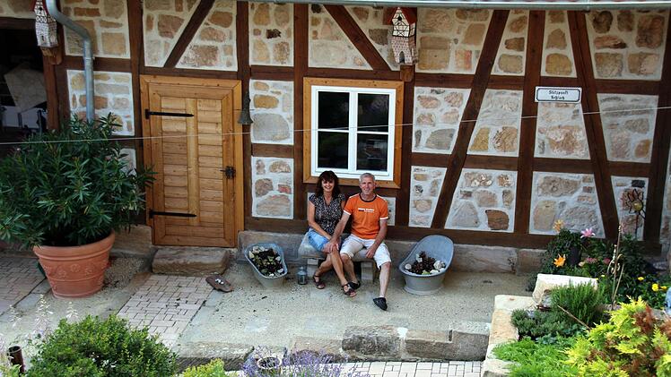 Die Hofmanns sitzen im Hof an ihrem denkmalgeschützten behutsam sanierten Haus. Foto: Bettina Knauth