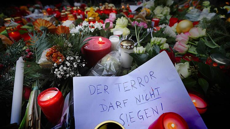 Kerzen und Blumen liegen am 20.12.2016 in Berlin am Ort des m&ouml;glichen Anschlags. Bei einem m&ouml;glichen Anschlag war ein Unbekannter am Montag (19.12.) mit einem Lastwagen auf einen Weihnachtsmarkt an der Ged&auml;chtniskirche gefahren. Auf dem Plakat steht: "Der Terror darf nicht siegen". Foto: Michael Kappeler/dpa