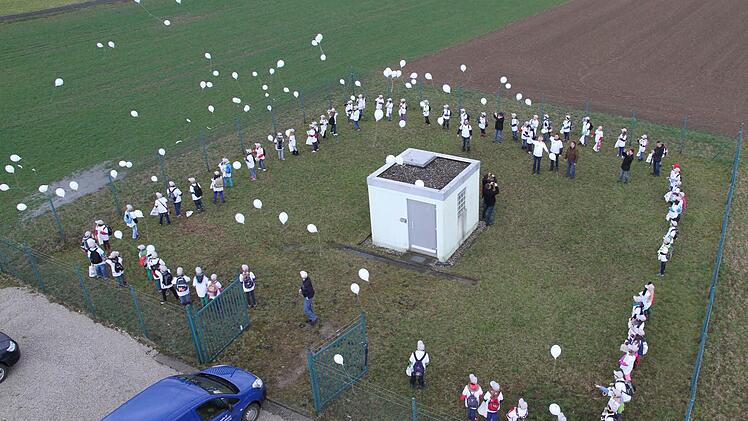Die Viertklässler der Schulen aus Eggolsheim und Buttenheim bilden um den Tiefbrunnen des Zweckverbandes einen Kreis und lassen Luftballons steigen.